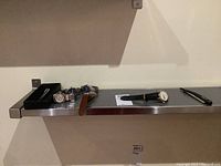 All watches and pen displayed on shelf with metal bracket