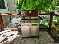Front view under tree on deck showing entire grill and side shelves