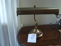 Side view of vintage brass bankers lamp on a wooden table showing base and shade detail