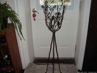 Full view of decorative metal floor-standing candelabra with four candle holders and leaf accents. Stands approximately 4 feet tall, positioned in front of a door.