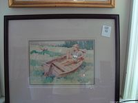 Framed watercolor style print by Bert Henderson featuring a young man seated in a small wooden boat, barefoot, with birds flying nearby on a body of water.