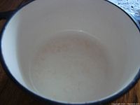 Interior view of the white enamel coated pot showing surface wear from use.