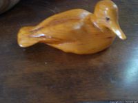 Side view of natural wooden duck decoy showing smooth carved details and finish.