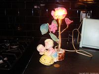 Night light base showing Dutch girl holding baby figurine, lamp cord, and coin for scale on black countertop.