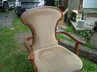Front view of the Bombay and Company wooden office chair showing the beige patterned upholstery on seat and backrest, curved wooden arms.