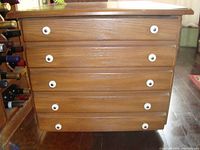 Front view of one wooden night stand showing four drawers with white circular knobs and wood grain finish.