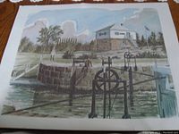 Framed print depicting a stone lock structure with visible water control mechanisms, set against a partly cloudy sky.