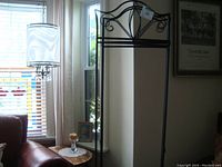 Black metal three-panel room divider skeleton frame without fabric panels, placed next to a window in a living room.