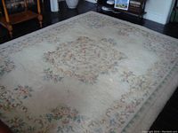 Full view of the large floral wool living room rug in cream color with pastel floral patterns around edges and center.