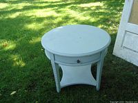 Full view of the light blue painted small round table showing the top surface and leg structure.