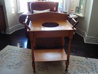 Front view of the antique wooden wash stand showing the hole for the ceramic basin and side rails.
