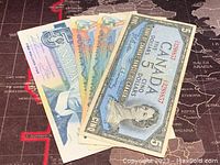 Photo showing the 5 Canadian dollar banknotes fanned out, displaying various designs and colors.
