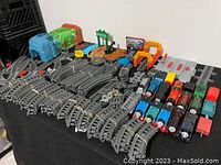 Wide view of all included trains, tracks, and accessories laid out on black surface.