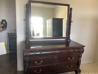 Front and side view of antique wooden dresser with large mirror and carved details.