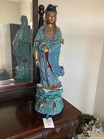 Full view of the large decorative statue positioned on a wooden surface with a mirror behind it.