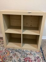 Front view of wooden bookshelf showing four square compartments and light wear marks.
