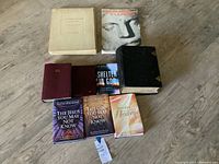 Full view of 9 books arranged on wooden floor showing diversity in sizes, genres, and conditions