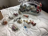 All miniature nativity scene figurines displayed on a quilted white surface including animals and wise men.