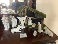 Photo showing entire nativity set with barn and white figurines arranged on a table