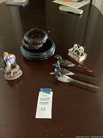 Photo showing a set of decorative items including wooden duck figurines on black bases, a cow figurine on a wooden cart, a snow globe on a base, and three additional dark wooden circular bases.