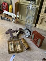 Overview of assorted decor items on floor including crosses, clock, jewelry box, printed panels, and decorative box.