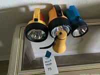 Set of four flashlights: three large different colored handheld flashlights and one small yellow flashlight with strap.