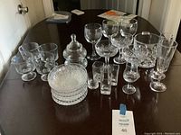 A variety of glassware and bowls displayed on a table including stemmed glasses, drinking glasses, stackable bowls, and a lidded jar.