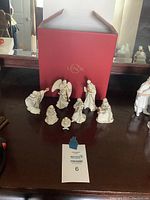 Full set of seven Lenox Christmas nativity miniature porcelain figurines displayed in front of their original Lenox box on a wooden surface