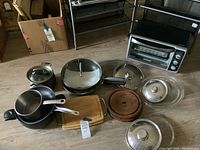 Photo showing the full collection of pots, pans, wooden cutting boards, glass baking dishes, and the small toaster oven in the background.
