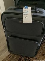 Set of three grey Tag soft cover luggage pieces with rolling wheels and handles visible. All luggage appear to be in lightly used condition with functional wheels.