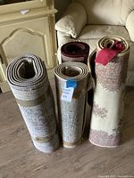 Four rolled area rugs placed on wooden floor next to couch and fireplace.