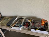 Wide view of multiple trays containing assorted tools and paint brushes arranged on a table