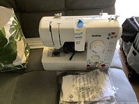 Brother sewing machine model JX2517 on a surface with power cord and manual.