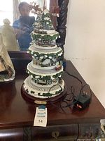 Full view of the multi-tiered Thomas Kinkade Wonderland Express with light on top and miniature train track around tiers.