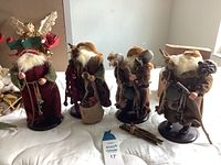 Full view of four traditional decorative Santa Claus figures standing on a white surface, showing overall lot contents.