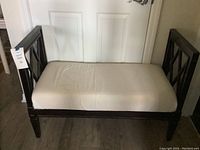 Front and side view of a wooden end of bed bench with light-colored cushion seat, showing overall condition and wear.