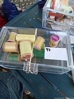 Clear acrylic organizer with multiple spools of vintage sewing threads in mixed green and yellow colors inside