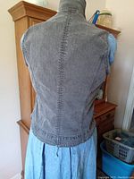 Back view of the gray denim vest showing zipper closure and detailed stitching.