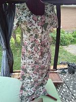 Front view of a fitted floral dress on a dress form, displaying the floral pattern and short sleeves.
