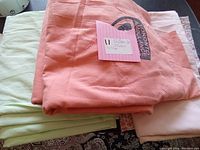 Peach-colored sheet and light green sheet folded together with a pink note on top.