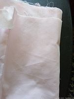 Folded light pink broadcloth fabric with visible smooth, uniform texture.