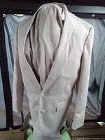 Front view of the tan men's suit jacket on a mannequin showing single-breasted style with notch lapel and two buttons.