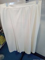 White knit long skirt hanging on clips showing length and texture.