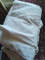 Folded white flat sheet shown on a dark surface