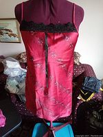 Red floral satin slip dress on mannequin showing black lace trim at bust and thin shoulder straps