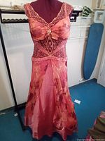 Front view of the coral formal gown on a mannequin, showing silk overdress with floral pattern, beaded waist detail, and gathered bust with decorative brooch.