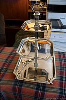 Side view of the three-tier Godinger silver plate stand showing three octagonal trays stacked vertically with central handle.