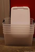 Stacked five large clear plastic storage totes with white lids and black handles, showing overall set condition.