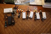 Six Christmas village lighting accessories including five street lamps with wreaths and a railway crossing light with flashing red lights and stop signs laid out on a table.