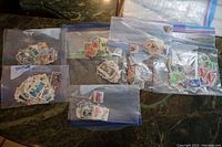 Eight resealable plastic bags filled with various used South African postage stamps of multiple colors and designs.
